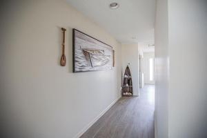 a white hallway with a painting on the wall at Ohana Tides Home in Holden Beach