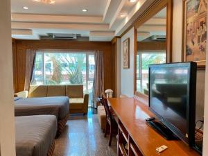 a hotel room with a television and a bedroom at New Siya in Maha Sarakham