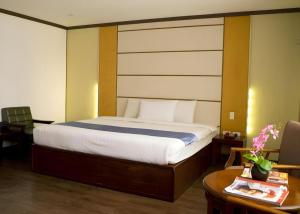 a bedroom with a bed and a desk and a table with a table at Horizon Hotel in Olongapo