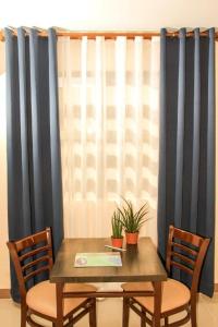 a table with two chairs and a window with blue curtains at Time Travellers Hotel in Manila