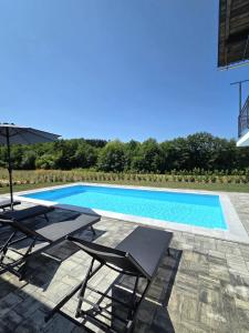 a swimming pool with two chairs and an umbrella at Under The Castle in Dob