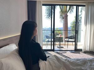 a woman sitting on a bed looking out the window at Mountain Hill in Mai Sơn +12 photos