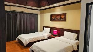 a hotel room with two beds and a lamp at King Hotel in Ban Tha Phae