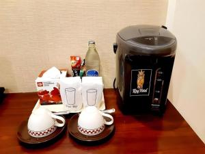 a coffee maker and two mugs next to a toaster at King Hotel in Ban Tha Phae