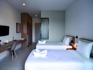 a hotel room with two beds and a desk and a television at @Sleep in Ban Rang Faet