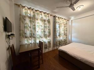 a bedroom with a bed and a desk and curtains at City Star in Srinagar
