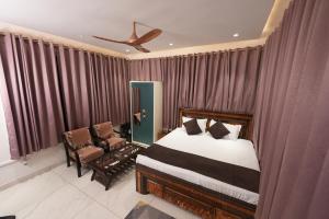 a bedroom with a bed and a chair and curtains at hotel baromas retreat in Jawālāpur