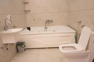 a bathroom with a tub and a toilet and a sink at hotel baromas retreat in Jawālāpur +39 photos