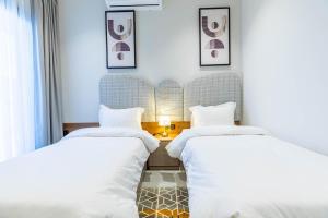 two beds in a hotel room with white sheets at Amber Hospitality - Arrawdha in Riyadh
