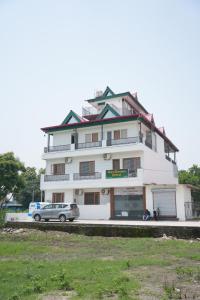 a white building with a car parked in front of it at hotel baromas retreat in Jawālāpur