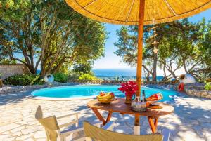a table with an umbrella next to a pool at Villa Nionios in Vlachopoulátika