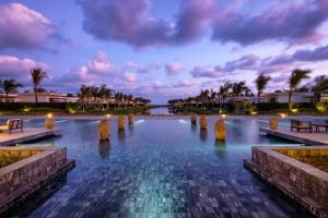 a pool of water with benches and palm trees at Meliá Ho Tram Beach Resort in Ho Tram