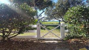 a white gate in a field with trees at 18 On Main in Wooli +10 photos