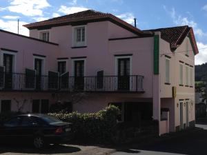 a pink house with a car parked in front of it at Hotel Vale Verde in Furnas