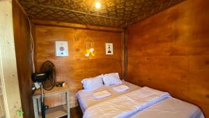 a small bedroom with a bed and a fan at Kampa Lodge in Tano
