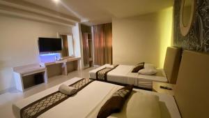a hotel room with two beds and a television at Hotel Grand Rosela in Yogyakarta