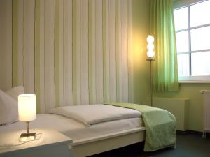 a bedroom with a bed with a lamp and a window at Altes Kasino Hotel am See in Neuruppin