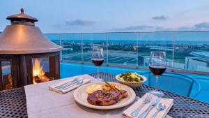 a table with a plate of food and glasses of wine at Seogwipo Dawa Pool Villa Pension in Seogwipo