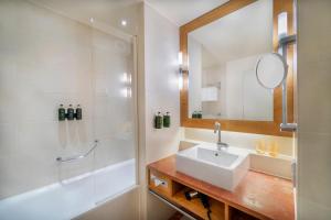 a bathroom with a sink and a shower and a mirror at Meliá Berlin in Berlin