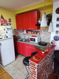 a kitchen with red cabinets and a white refrigerator at Agape in Niš