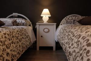una camera con 2 letti e una lampada su un comodino di T T house a La Spezia