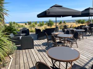 a wooden deck with tables and chairs and umbrellas at Hotel Castel Moor in Le Croisic