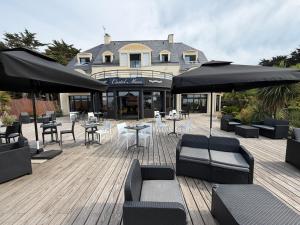 a wooden deck with tables and chairs and umbrellas at Hotel Castel Moor in Le Croisic