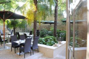 un restaurant avec des tables, des chaises et des palmiers dans l'établissement Hotel Spa Le Calendal, à Arles