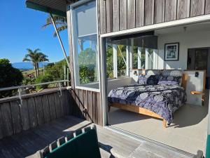 a bedroom on the balcony of a house at The Nikau Loft in Onetangi