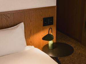 a bedroom with a bed and a lamp on a table at WPÜ HOTEL Shinjuku in Tokyo
