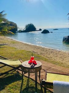 a table on the beach with a red flower on it at Ankavia Lodge in Sainte Marie