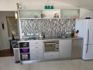 a kitchen with a sink and a refrigerator at The Nikau Loft in Onetangi