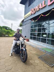a man sitting on a motorcycle in front of a building at Vighnaharta Homestay in Ganpatipule