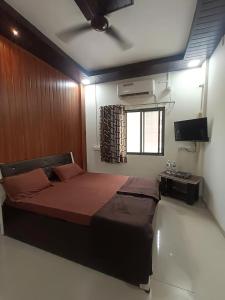 a bedroom with a bed and a television in it at Vighnaharta Homestay in Ganpatipule