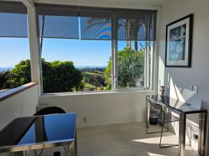 a room with a large window and a table and chairs at The Nikau Loft in Onetangi