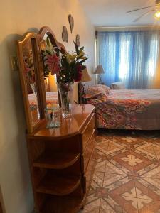 a bedroom with a dresser with a vase of flowers on it at Edna's GuestHouse in Siquirres