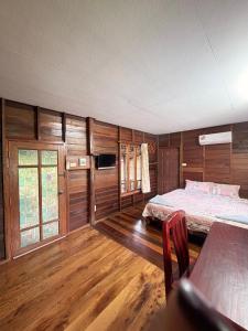 a bedroom with two beds and a tv and wooden walls at Suchanaree@Laemngop in Trat