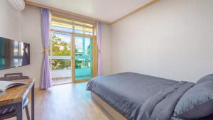 a bedroom with a bed and a window and a desk at Goseong Gamnamu Pension in Goseong