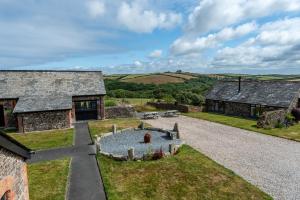 an external view of a stone house with a pond in the yard at Warner - Treworgie Barton Cottages in Bude