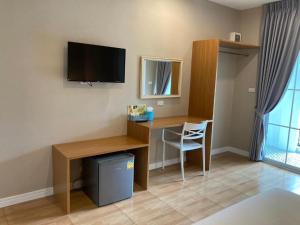 a room with a desk with a television and a chair at Thong Prachok Hotel in Sakon Nakhon