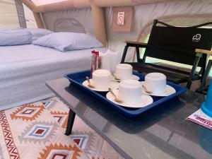 a tray with cups and saucers on a table in a tent at Riverside Glamping Resort Kanchanaburi in Kanchanaburi City