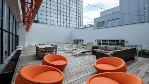 a balcony with orange chairs and tables on a building at CozySuites at LTV in Dallas