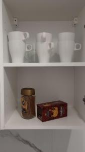 a shelf with white cups and a box on it at Self check-in Apartament Poznań Marcelin Lotnisko Ławica Szpitale Uczelnie in Poznań