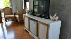 a living room with a flat screen tv on a white cabinet at Gin's Greenery Resort in Ban Hua Wiang