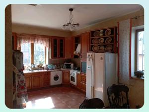a kitchen with wooden cabinets and a white refrigerator at Вовча хижа in Khmelnytskyi