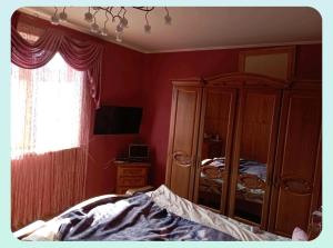 a bedroom with red walls and a bed and a dresser at Вовча хижа in Khmelnytskyi