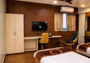 a hotel room with two beds and a flat screen tv at DEO SIGNATURE SUITE Hotel in Rānchī