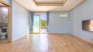 an empty living room with wood floors and a television at Samcheok Greenhyang Pension in Samcheok