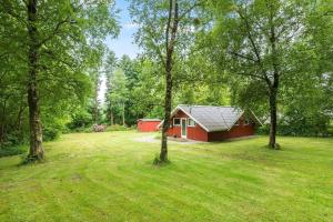 a red cabin in the middle of a field with trees at 0649-Toftlund-Ostmarken-49 in Toftlund