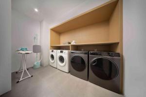 a laundry room with two washing machines and a table at Hangzhou East Railway Station Qiantang Jiake Hotel in Wuhang